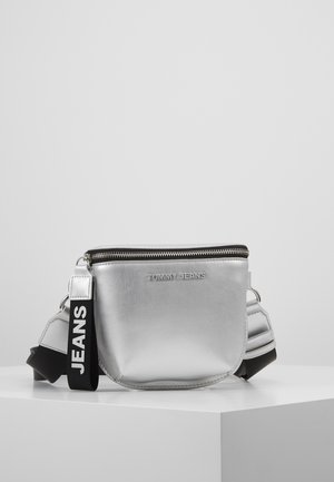 Borsa a spalla metallica argentea con chiusura a zip, caratterizzata da una superficie testurizzata e una tracolla nera con l'etichetta "JEANS" per un tocco di stile in più.