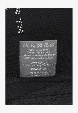 Schwarze, reflektierende lange Leggings mit einer glatten Textur, ausgestattet mit einem Pflegeetikett in Grau, das Pflegehinweise und einen Website-Link enthält.