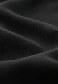 Schwarzer Stoff mit einer glatten Textur und sanften Falten, der ein feines Webmuster und eine leicht reflektierende Oberfläche zeigt.