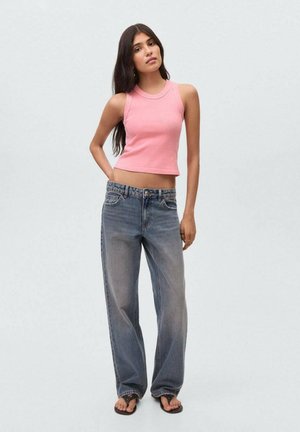 Un haut court rose avec une texture côtelée, associé à un jean bleu clair ample et des tongs noires.