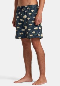 Bañador navy con un patrón floral que presenta flores blancas y hierba verde. Cintura elástica con cordón y parche de logo.