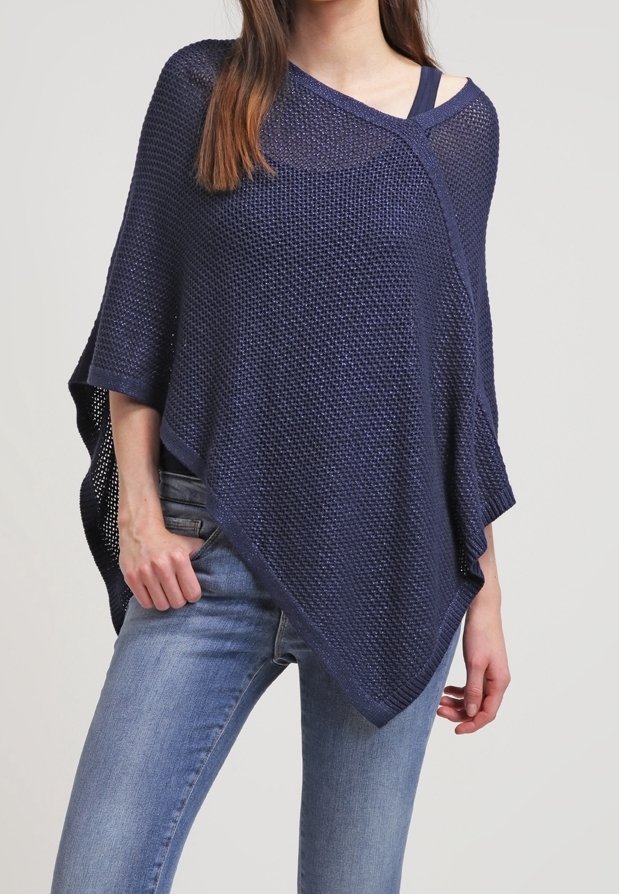 Marinblå stickad poncho med asymmetrisk design, med en lös passform och strukturerad tyg, bärs över en enkel topp och jeans.