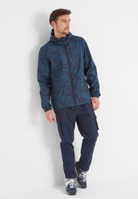 Navy patterned jacket with hood, long sleeves, and zip closure. Paired with navy cargo pants. Sneakers with white laces and gray accents.