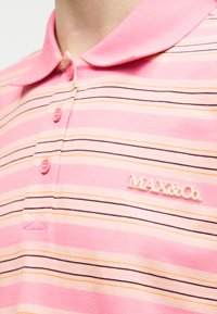 Ροζ πόλο μπλούζα με οριζόντιες κίτρινες, λευκές και μαύρες ρίγες, τρία ροζ κουμπιά και το λογότυπο "MAX&Co." στο στήθος.