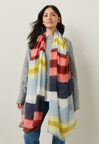 Pañuelo ligero y transparente con rayas horizontales en azul, coral, amarillo y azul marino. Tejido texturizado con un diseño fluido.