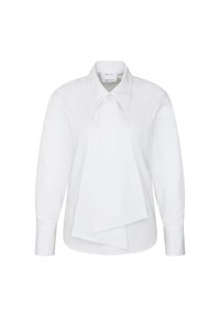 Blouse blanche à manches longues avec grand col pointu et grand nœud sur le devant, présentée sur un fond uni.
