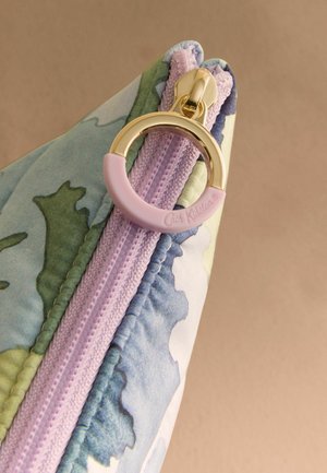 Torebka z tkaniny w kwiatowy wzór z fioletowym zamkiem błyskawicznym i złotym okrągłym uchwytem częściowo pokryta różowym gumowym uchwytem.