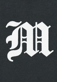 Tessuto nero con una grande grafica ricamata in bianco delle lettere "MA" in un carattere gotico stilizzato con elementi decorativi.