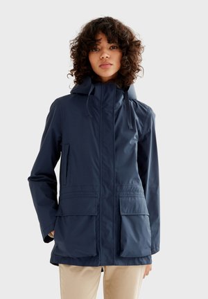 Chaqueta de lluvia azul marino con capucha, cremallera frontal y dos grandes bolsillos frontales. Material suave y ligero con cordones ajustables en el collar.