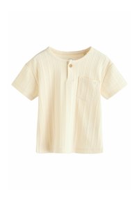 T-shirt crème à manches courtes avec une texture côtelée, encolure ronde, fermeture à un bouton, et une petite poche poitrine.