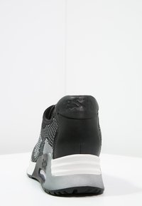 Černé a šedé tenisky s horní částí z mesh materiálu, texturovanou černou patou a bílou mezipodešví. Obsahují hladkou podrážku s drážkami pro trakci.