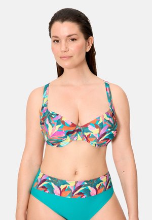 Mujer con cabello lacio y oscuro, vestida con un bikini colorido de estampado de hojas y braguitas de bikini de talle alto en color teal.