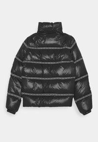 Doudoune noire avec un col haut, présentant des sections matelassées horizontales et des bandes de marque blanches le long des coutures.