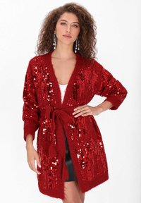 Czerwony kardigan z cekinami o pluszowej fakturze, otwarty z przodu, z długimi rękawami i dopasowanym paskiem, z połączeniem błyszczących i matowych cekinów.