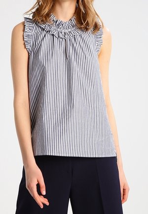 Ärmellose blau-weiß vertikal gestreifte Bluse mit gerafftem Kragen und Ärmeln, getragen mit dunkler Hose.