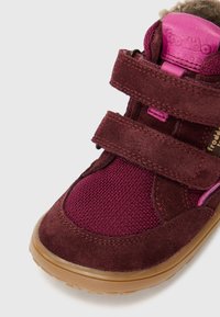 Chaussure de sport avec bride Velcro en suède bordeaux et maille, dotée d'un col rembourré, d'une semelle en caoutchouc et d'accents roses sur la languette et la bride.