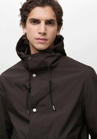 Jachetă impermeabilă maro cu guler înalt, șnururi și nasturi prin apăsare; textură netedă, având un design minimalist.