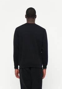 Zwarte sweatshirt met een ronde halslijn en lange mouwen, met een eenvoudig ontwerp en geribde boorden en zoom. Zacht, gestructureerd materiaal.