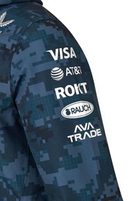 Niebieska kurtka w kamuflażowy wzór o gładkiej teksturze. Posiada białe logo Visa, AT&T, ROKT, RAUCH i AVA TRADE na lewym rękawie.
