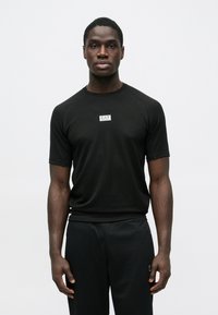 Melna sporta T-krekls ar īsām piedurknēm, uz krūtīm neliels EA7 logo, izgatavots no viegla, elpojoša materiāla.