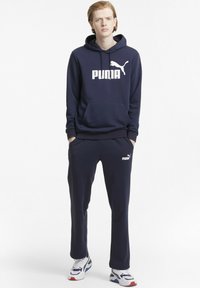 Námořnický modrý mikina s bílým logem "PUMA", přední kapsa, odpovídající námořnické tepláky s malým logem. Pohodlná tkanina, uvolněný střih.