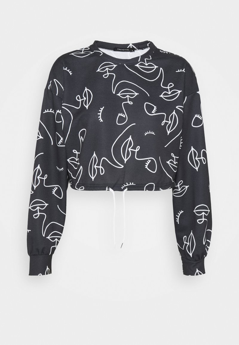 Sudadera negra recortada hecha de tela suave, presenta patrones de arte lineal abstracto en blanco y puños elastizados con dobladillo ajustable.