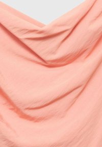 Tissu doux et drapé dans une couleur rose pastel. La texture semble lisse avec de douces ondulations et plis, créant un aspect fluide.