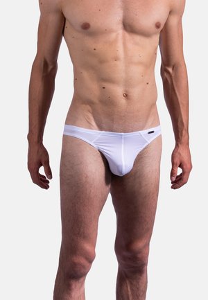 Männlicher Oberkörper und Beine, die weiße gerippte Slips unter einem schlichten hellen Hintergrund tragen.