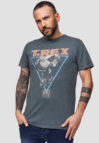 Grijs T-shirt met korte mouwen met een grote afbeelding van een T. Rex binnen een blauwe driehoek, met "T.REX" erboven en "1993 TOUR" eronder.