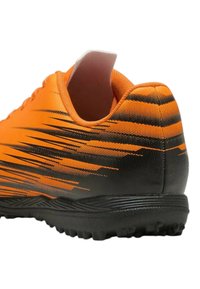 Scarpa da calcio arancione con accenti neri, caratterizzata da una parte superiore testurizzata, un collo curvo e una suola in gomma progettata per la trazione.