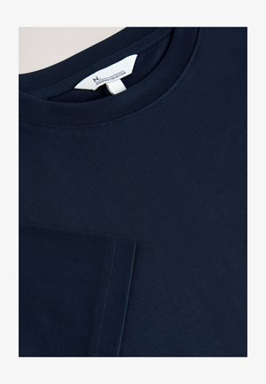 Tumesinine puuvillane T-särk lühikeste varrukatega, ringkaelusega ja rinnataskuga. Silmapaistev peen õmblus ja sile pind.