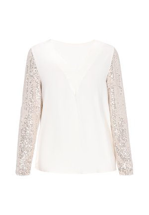 Crème blouse met een V-hals, voorzien van lange mouwen versierd met zilveren pailletten. De soepele textuur op het lichaam contrasteert met de glanzende mouwen.