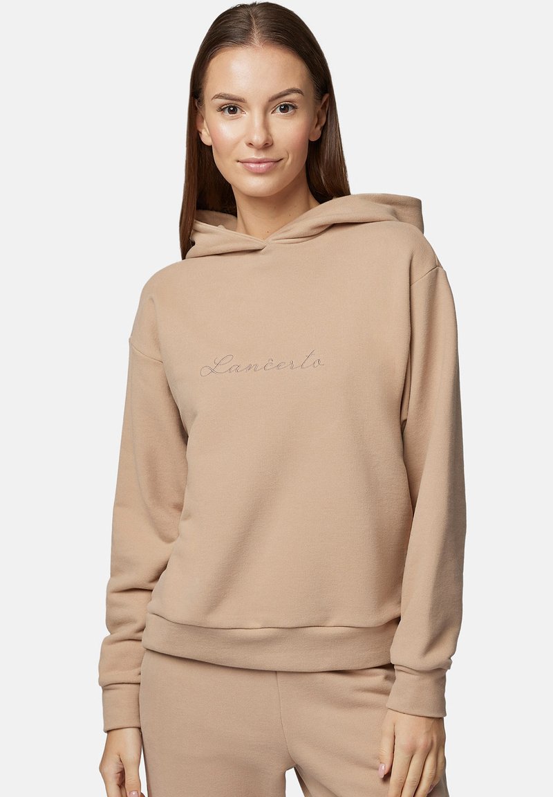 Beżowa bluza z kapturem o miękkiej teksturze i luźnym kroju. Posiada haftowane logo w jaśniejszym odcieniu na piersi.