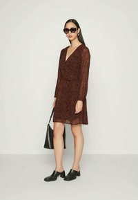 Vestido bordô com padrão de zebra, mangas longas e decote em V, combinado com tamancos pretos e uma mala preta texturizada. Tecido suave e leve.