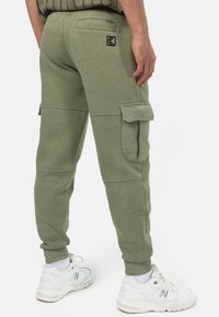 Gröna cargobyxor i sweatpantsmodell med sidofickor, ribbade muddkanter och en liten logotyp på bakfickan. Tillverkade av mjukt, strukturerat tyg.