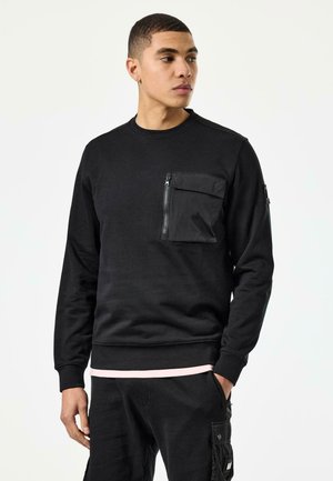 Felpa nera in misto cotone con tasca sul petto con zip, polsini e orlo a costine, caratterizzata da una texture liscia e una vestibilità comoda.