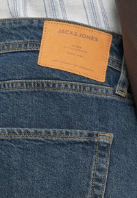 Τζιν παντελόνια σε σκούρο μπλε με ορατές ραφές και καφέ δερμάτινη ετικέτα με την ένδειξη "JACK & JONES." Διαθέτουν πίσω τσέπες και κλασική εφαρμογή.
