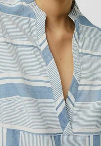 Sininen ja valkoinen raidallinen paita, jossa on läpivientikaulus, sekoitus vaakasuoria ja pystysuoria viivoja sekä pehmeä, kevyt kankaan rakenne.