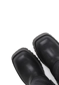Black waterproof boots with a square toe, textured leather upper, and rubber sole with deep treads for grip.