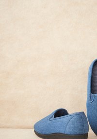 Blauwe instapschoenen van zacht materiaal, met een lage profiel en elastische zijpanelen voor gemakkelijk aan- en uittrekken. Zwarte rubberen buitenzool voor grip.