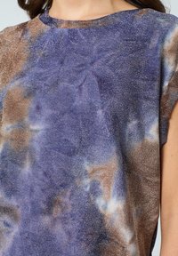 Lila och brun tie-dye-topp med metallisk glans, bred urringning och korta ärmar. Mjuk, strukturerad tyg med en följsam design.