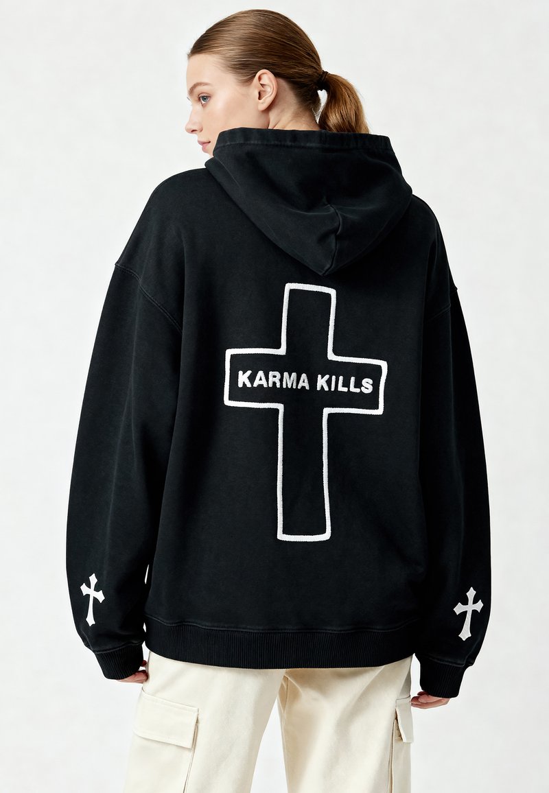 Felpa nera con cappuccio, dalla vestibilità oversize, con una grande croce contornata di bianco e il testo "KARMA KILLS" sulla schiena, oltre a croci bianche sulle maniche.