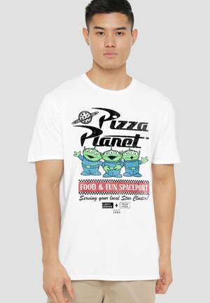 Junger Mann trägt ein weißes T-Shirt mit grünen Alien-Figuren und dem Text "Pizza Planet Food & Fun Spaceport".
