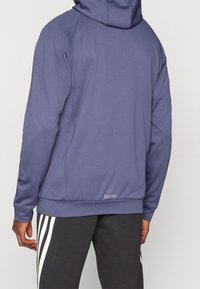 Felpa con cappuccio in morbido e elasticizzato tessuto viola con vestibilità ampia. Presenta polsini a coste, una tasca frontale e il logo 'COLD.RDY' sull'orlo.