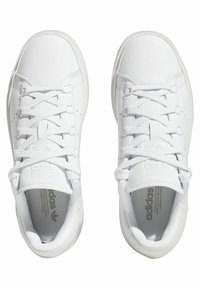 Vita atletiska sneakers med en slät läderexteriör, platta snören, vadderad krage och en subtil logotypdetalj på tungan och inlägget.