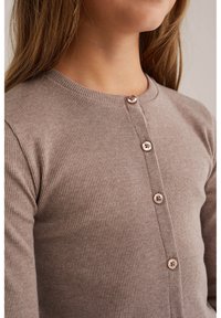 Brauner gerippter Cardigan mit rundem Ausschnitt und fünf passenden Knöpfen auf der Vorderseite, der eine glatte Textur und eine figurbetonte Silhouette aufweist.