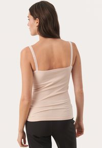 Lichtroze mouwloze tanktop van een zachte, elastische stof, met dunne bandjes en een aansluitende pasvorm.