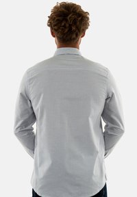 Camicia a maniche lunghe a righe verticali bianche e azzurro chiaro, con colletto standard, spalla posteriore e polsini con bottoni.