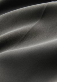 Glattes, hellgraues Gewebe mit feiner horizontaler Rippstruktur und sanften Falten, die weiche Schatten und Highlights erzeugen.