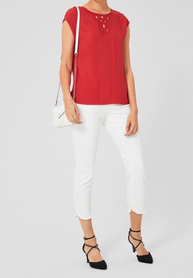 Rød kortærmet bluse med udskæringsdetalje, parret med hvide cropped jeans og sorte stiletter, kompletteret med en lille hvid håndtaske.